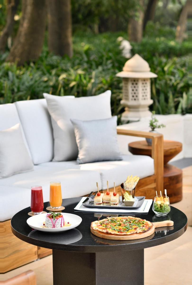 a table with two pizzas on it with a couch at Taj Mahal, New Delhi in New Delhi