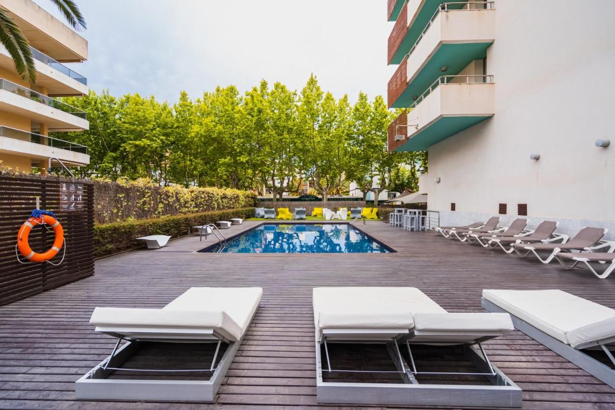 una piscina con tumbonas y un hotel en Magnolia Hotel - Adults Only, en Salou