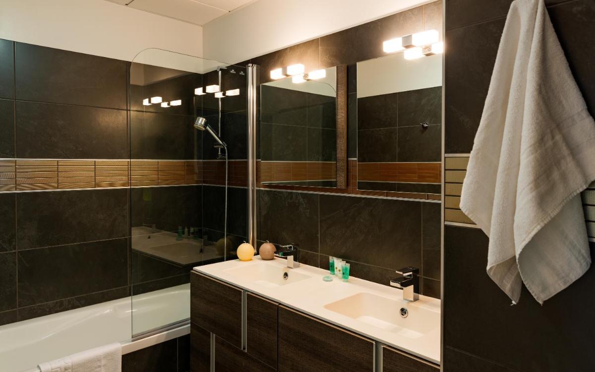 une salle de bain avec un lavabo et un miroir dans l'établissement Lagrange Vacances Les Patios Eugénie, à Biarritz