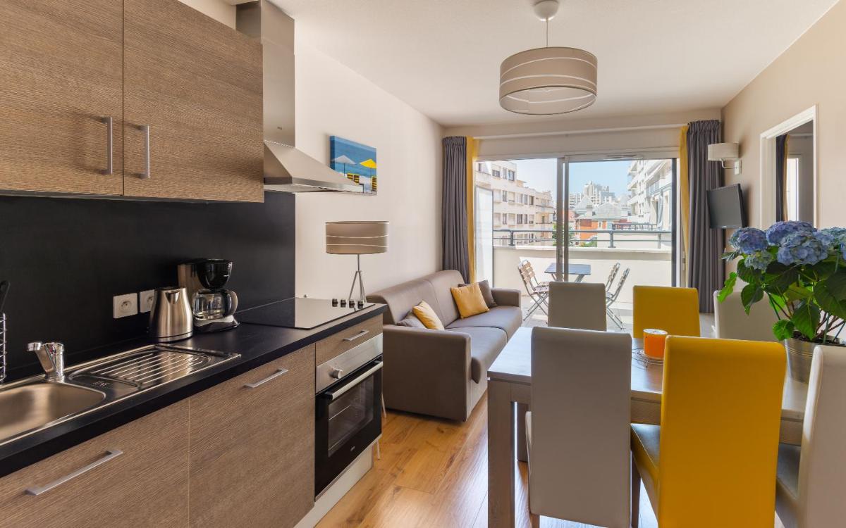 une cuisine et un salon avec une table et des chaises dans l'établissement Lagrange Vacances Les Patios Eugénie, à Biarritz