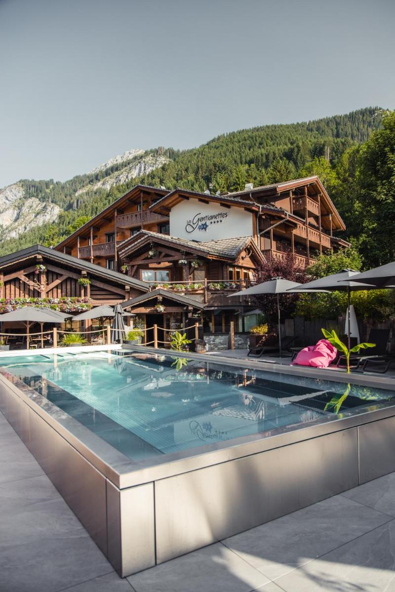 un hôtel avec une piscine devant un bâtiment dans l'établissement Les Gentianettes Hotel & Spa, à La Chapelle-dʼAbondance
