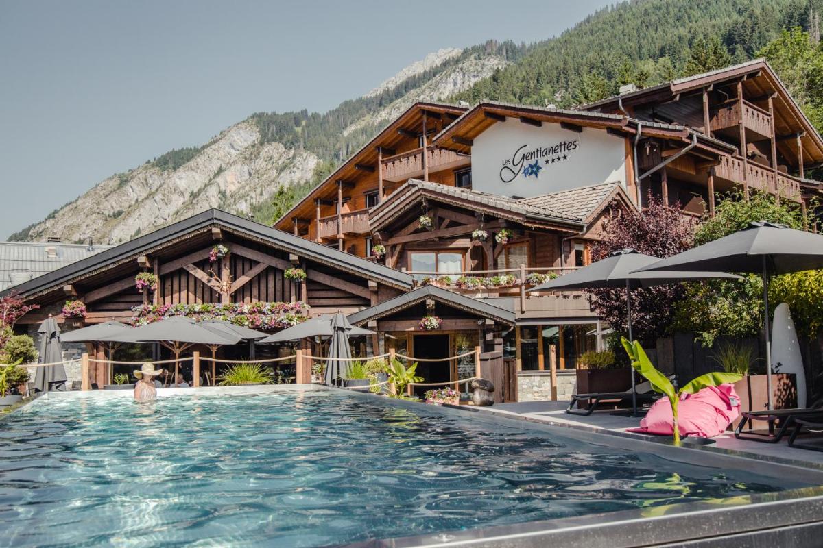 un hôtel avec une piscine devant un bâtiment dans l'établissement Les Gentianettes Hotel & Spa, à La Chapelle-dʼAbondance