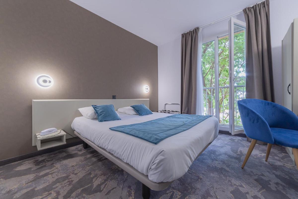 une chambre avec un grand lit et une chaise bleue dans l'établissement Relax'Otel & Spa, Le Barcarès, au Barcarès