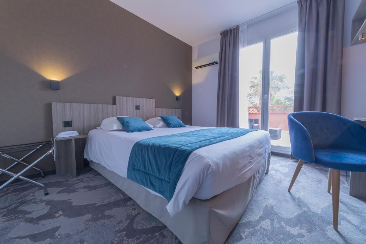 une chambre avec un grand lit et une chaise bleue dans l'établissement Relax'Otel & Spa, Le Barcarès, au Barcarès