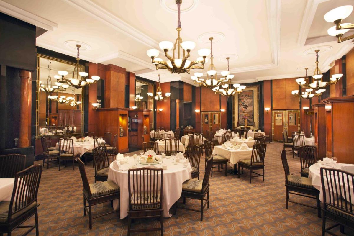 a dining room with white tables and chairs and chandeliers at Eros Hotel New Delhi, Nehru Place in New Delhi a dining room with white tables and chairs and chandeliers at Eros Hotel New Delhi, Nehru Place in New Delhi