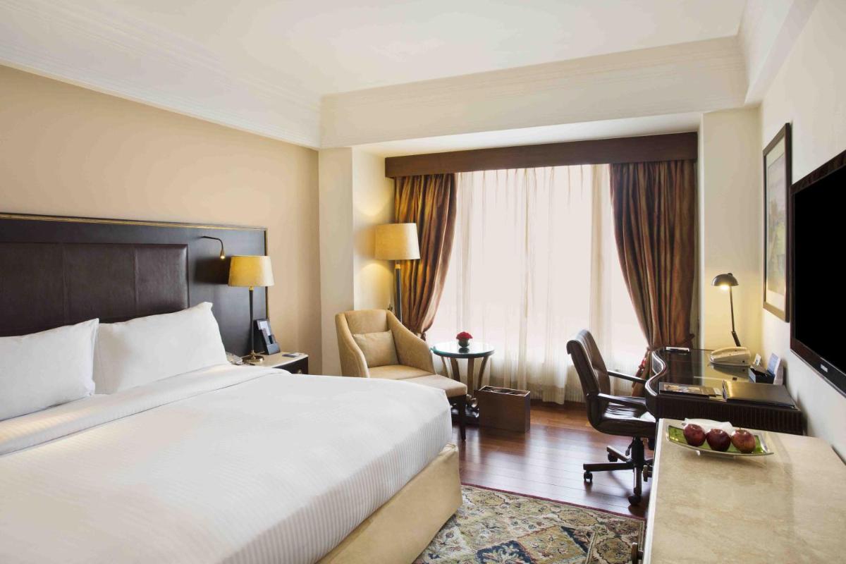 a hotel room with a large bed and a desk at Eros Hotel New Delhi, Nehru Place in New Delhi a hotel room with a large bed and a desk at Eros Hotel New Delhi, Nehru Place in New Delhi