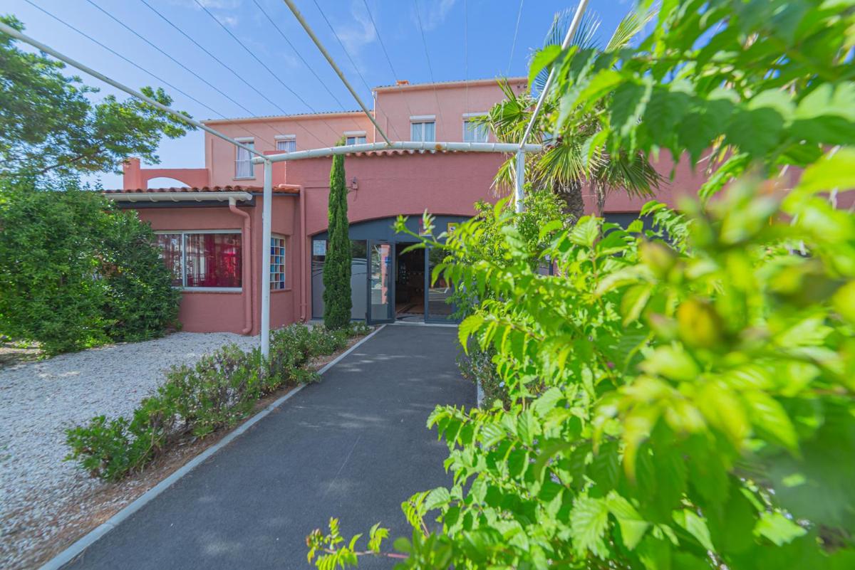 une maison rose avec une allée devant dans l'établissement Relax'Otel & Spa, Le Barcarès, au Barcarès 45 autres photos