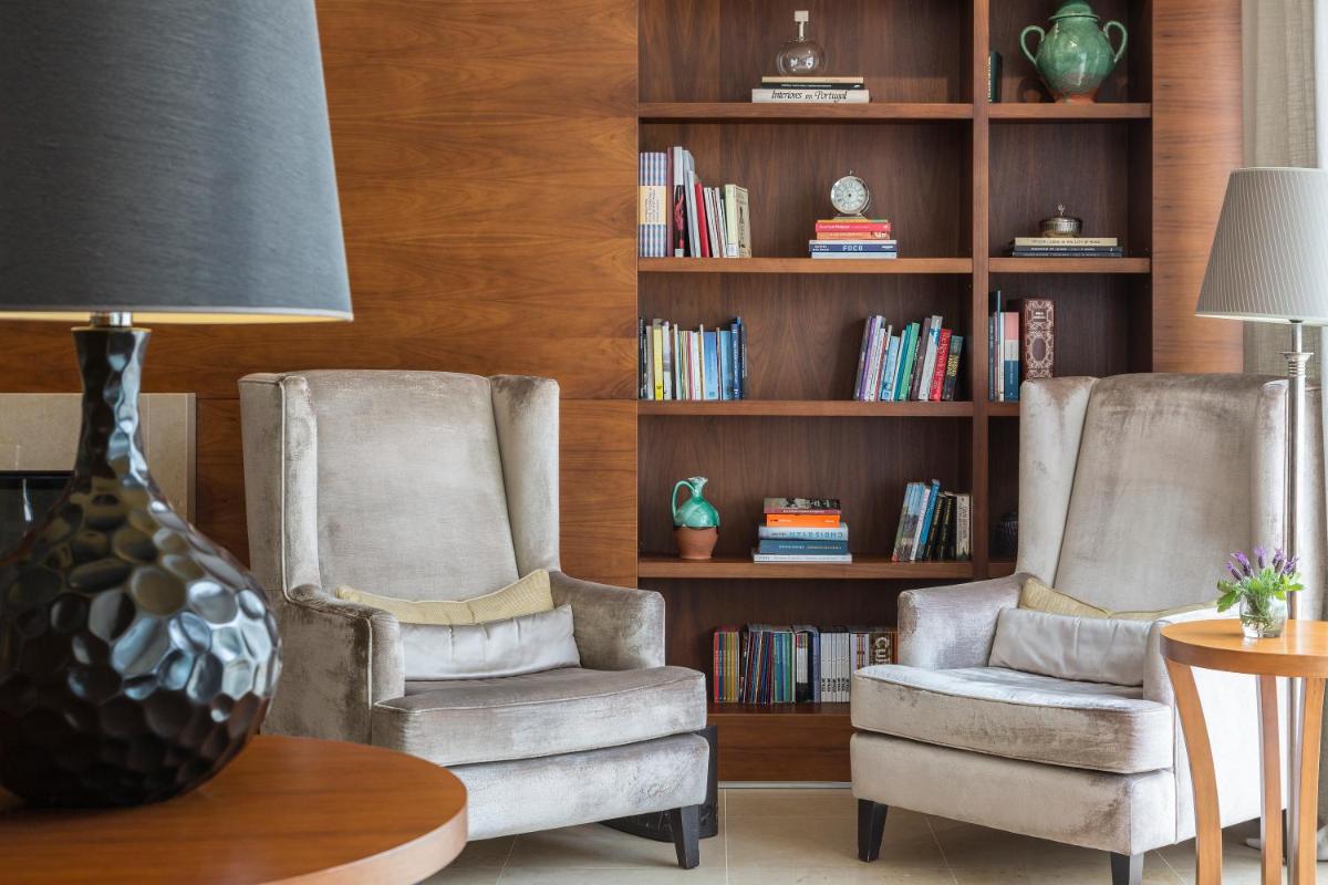 duas cadeiras em uma sala de estar com uma estante de livros em Hotel Dom Goncalo & Spa em Fátima mais 88 fotografias