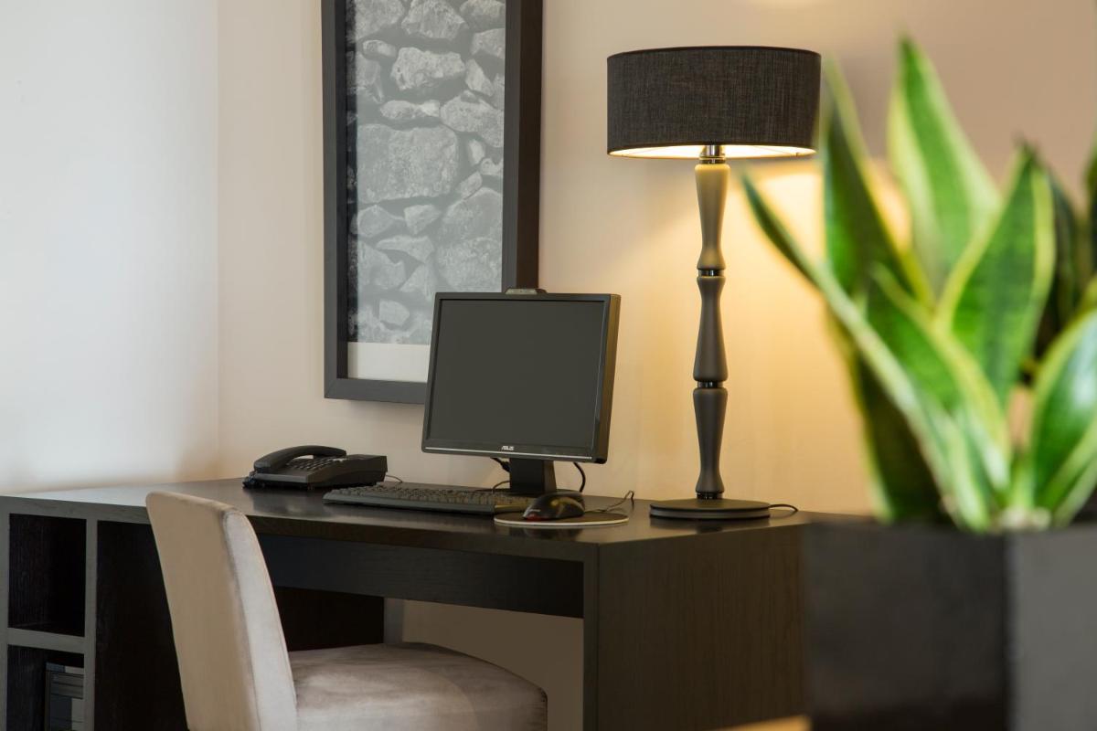 uma mesa com um computador e uma lâmpada em cima dela em Hotel Dom Goncalo & Spa em Fátima