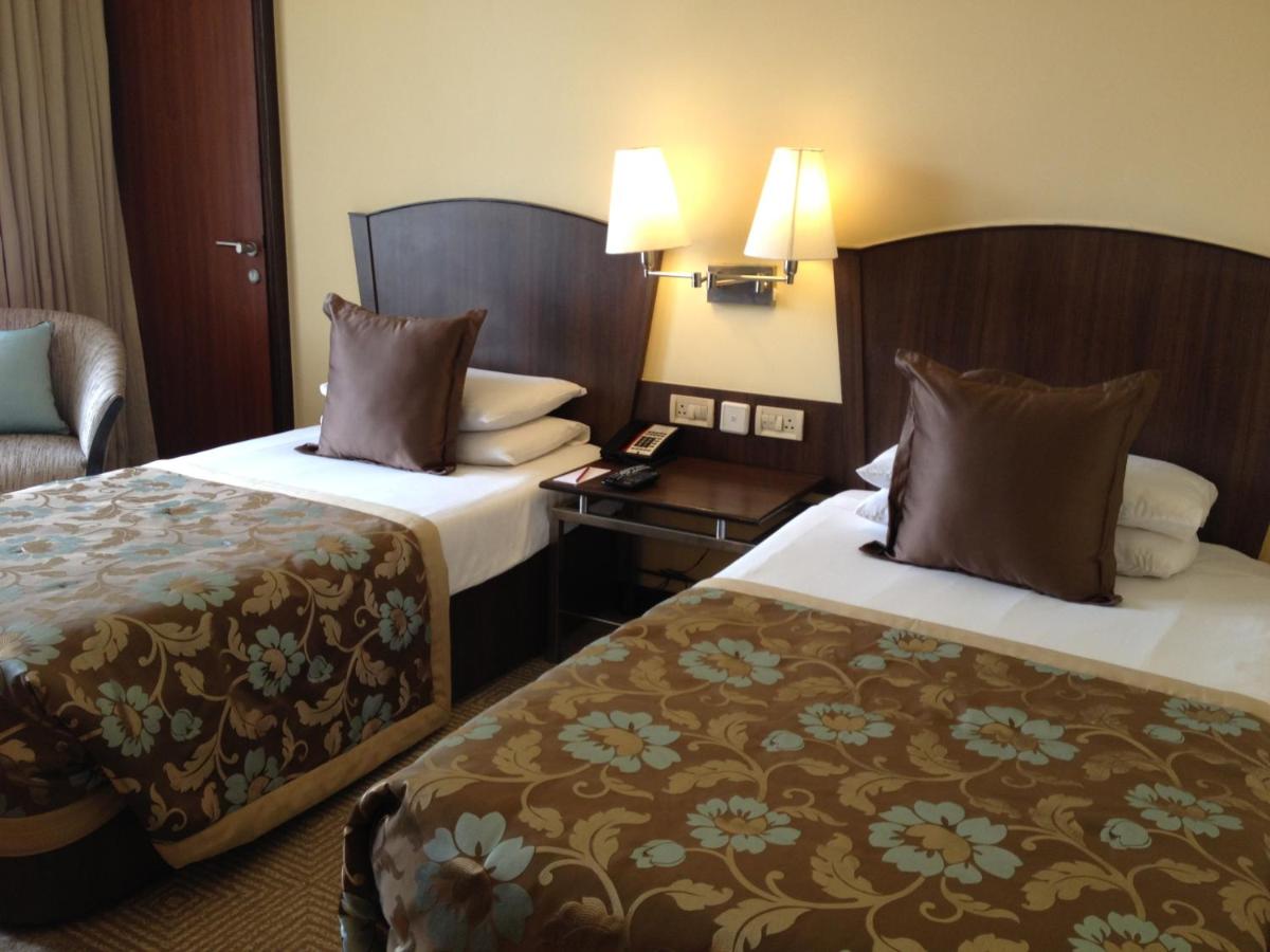 a hotel room with two beds and a chair at Blue Diamond Pune IHCL SeleQtions in Pune