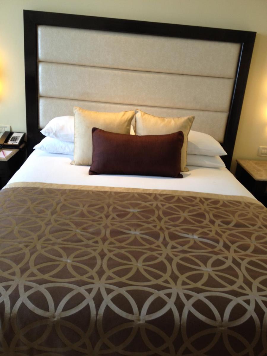 a large bed with a large headboard and pillows at Blue Diamond Pune IHCL SeleQtions in Pune