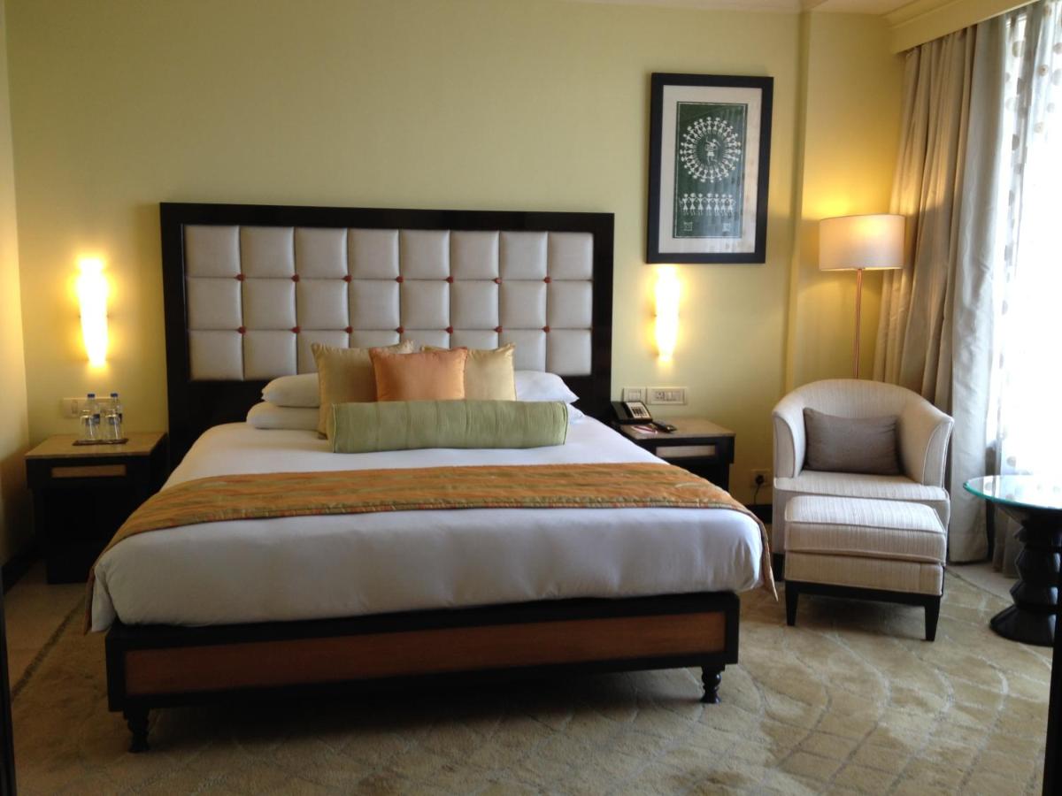 a bedroom with a large bed and a chair at Blue Diamond Pune IHCL SeleQtions in Pune