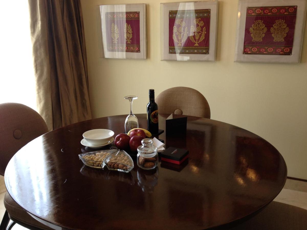a wooden table with a bottle of wine and fruit on it at Blue Diamond Pune IHCL SeleQtions in Pune