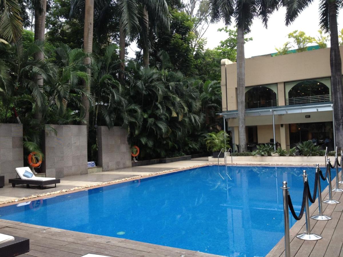 a swimming pool in front of a building with palm trees at Blue Diamond Pune IHCL SeleQtions in Pune