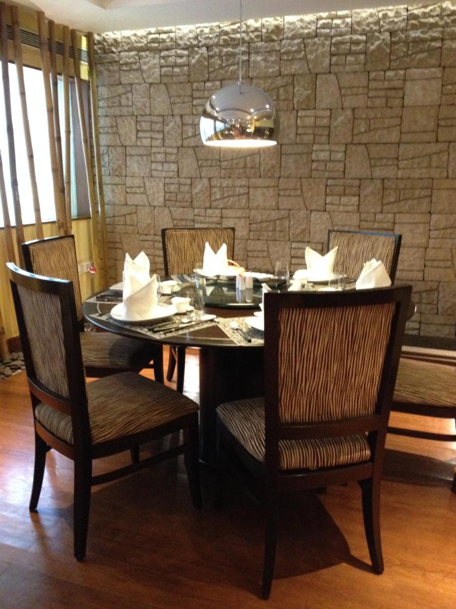 a dining room with a table and chairs and a stone wall at Blue Diamond Pune IHCL SeleQtions in Pune