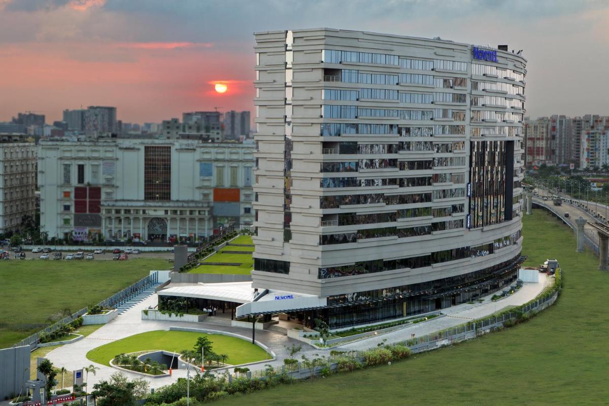 a tall white building with a park in front of it at Novotel Kolkata Hotel and Residences in Kolkata a tall white building with a park in front of it at Novotel Kolkata Hotel and Residences in Kolkata