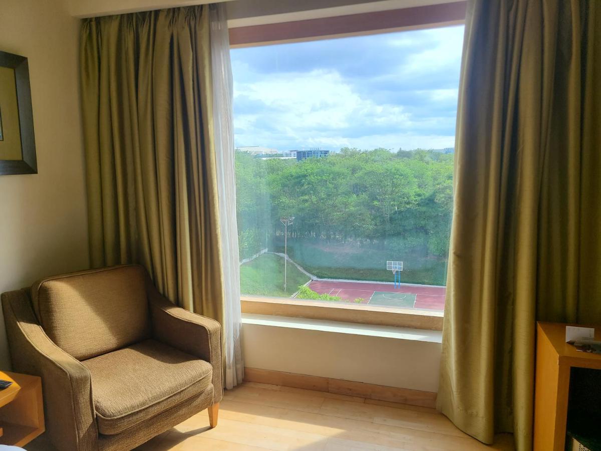 a room with a chair and a large window at Novotel Hyderabad Airport in Hyderabad
