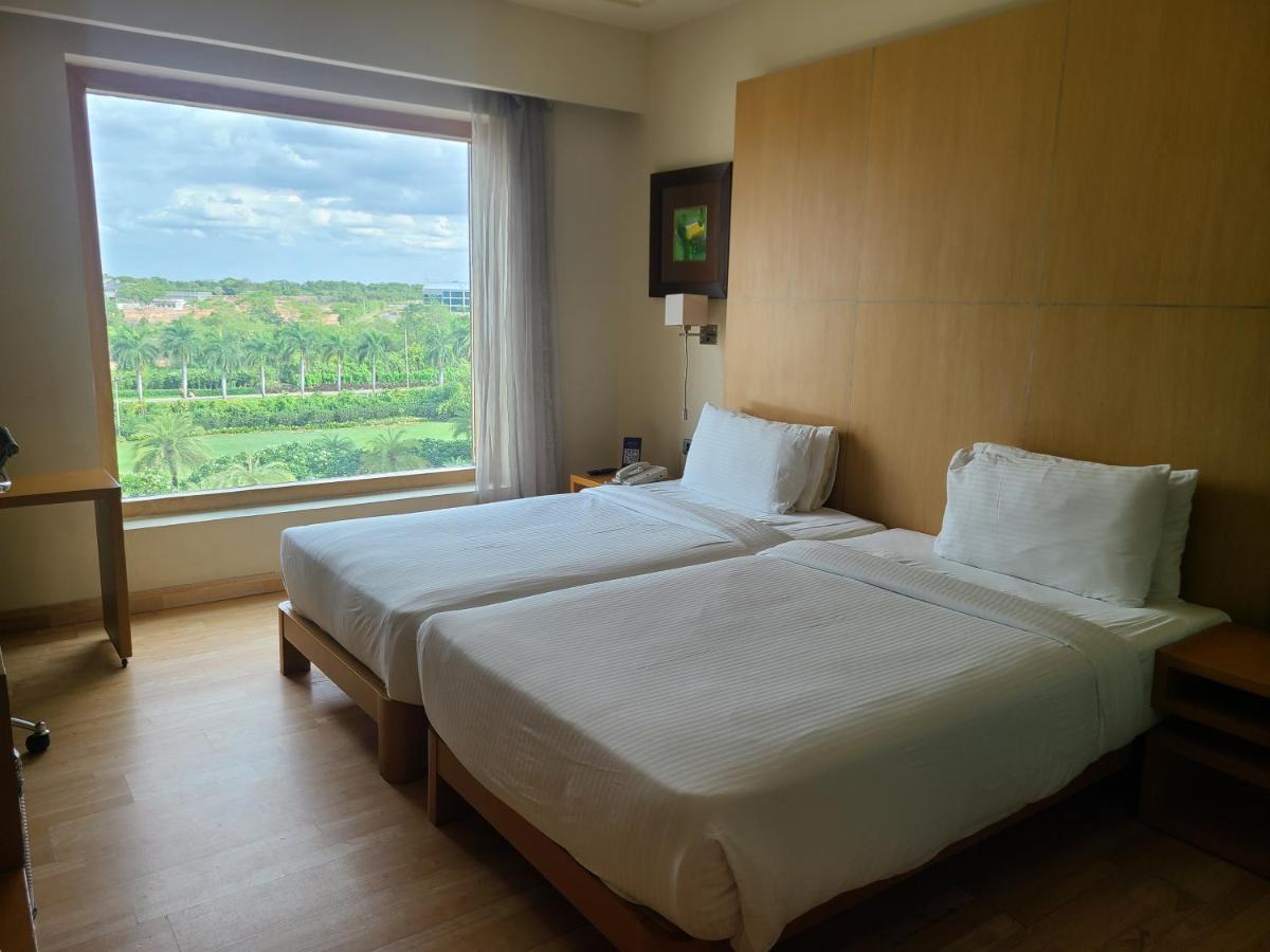 a bedroom with a large bed with a large window at Novotel Hyderabad Airport in Hyderabad