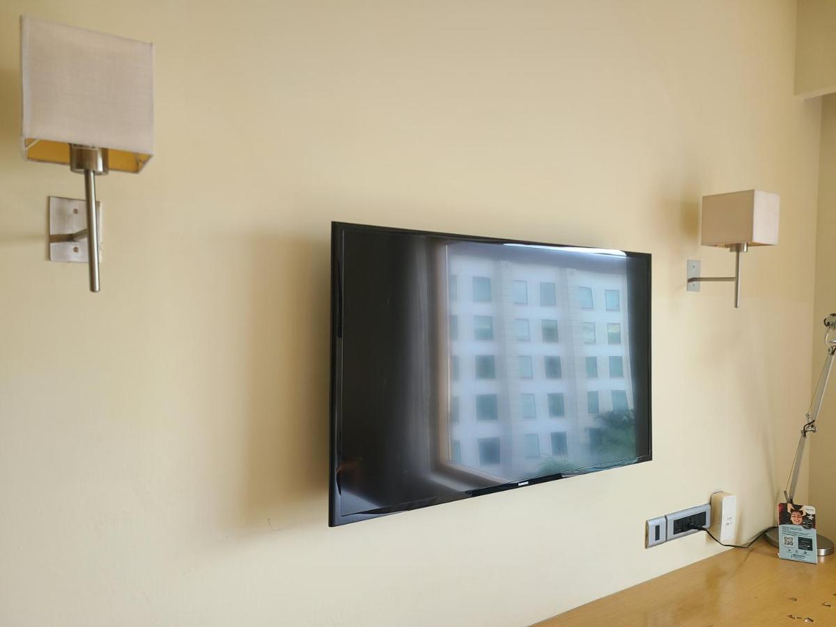 a flat screen tv on a wall with a window at Novotel Hyderabad Airport in Hyderabad