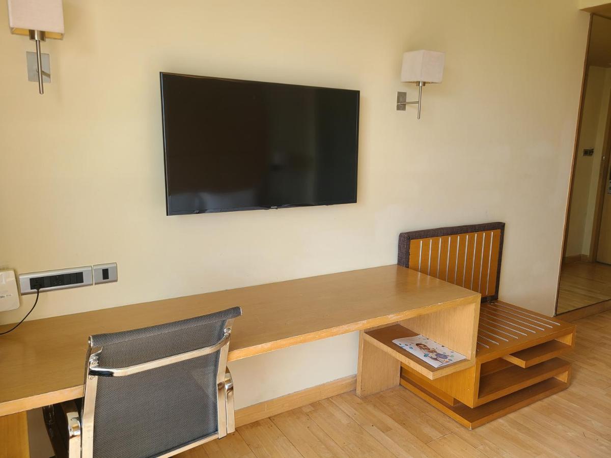 a room with a desk and a television on a wall at Novotel Hyderabad Airport in Hyderabad