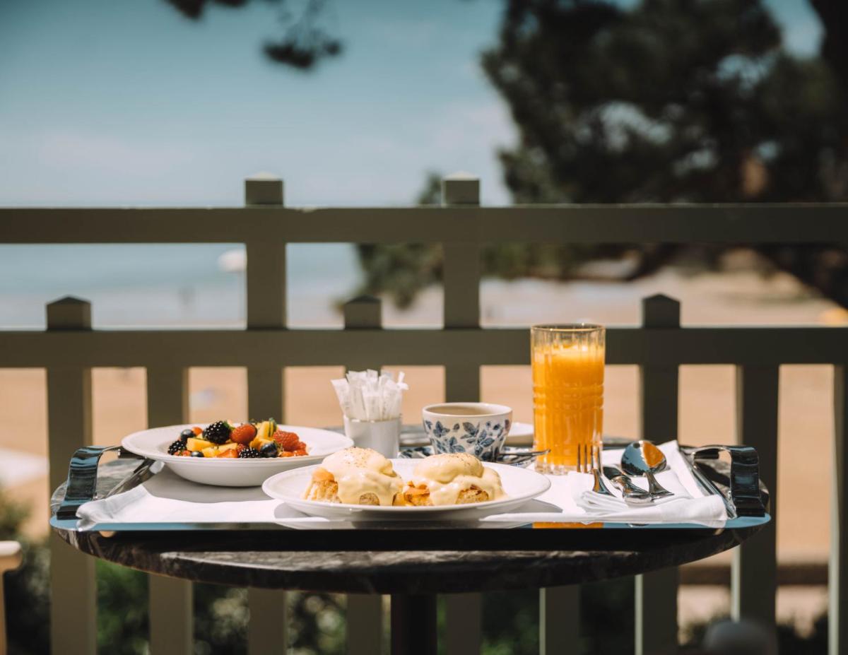 une table avec deux assiettes de nourriture et un verre de jus d'orange dans l'établissement Hôtel Hemen, à Saint-Palais-sur-Mer
