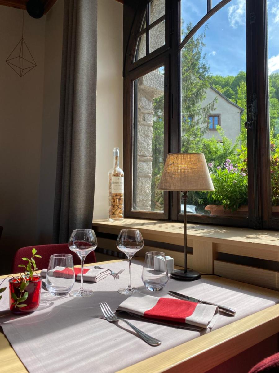 une table avec des verres à vin et une fenêtre dans l'établissement LE CLOS DES SOURCES Hôtel & Spa, à Thannenkirch
