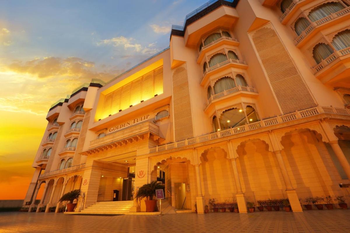 a large building with a sunset in the background at Golden Tulip Jaipur in Jaipur