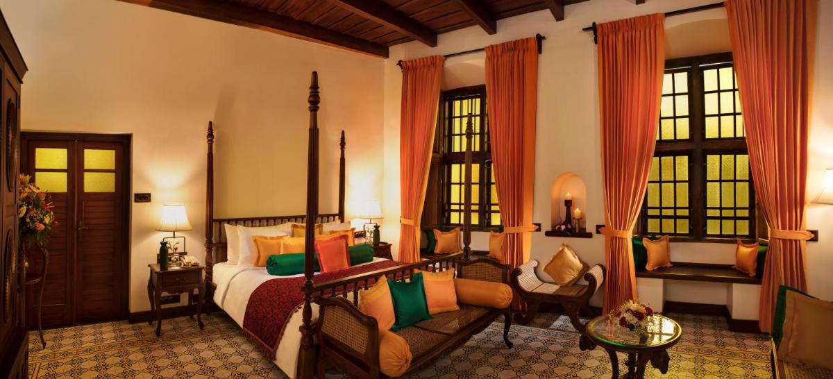 a bedroom with a bed and a couch and windows at Forte Kochi in Cochin