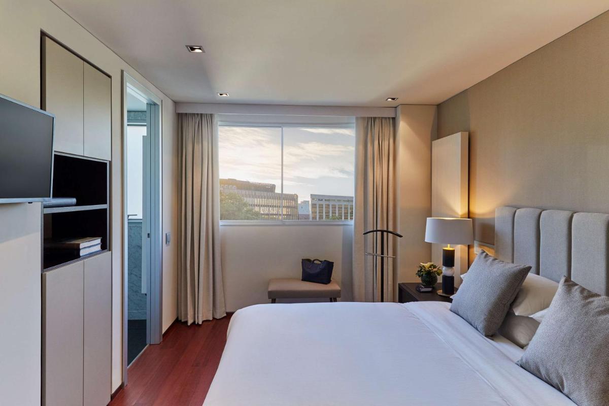 Una habitación de hotel con una cama grande y una ventana. en Hyatt Regency Madrid Residences, en Madrid