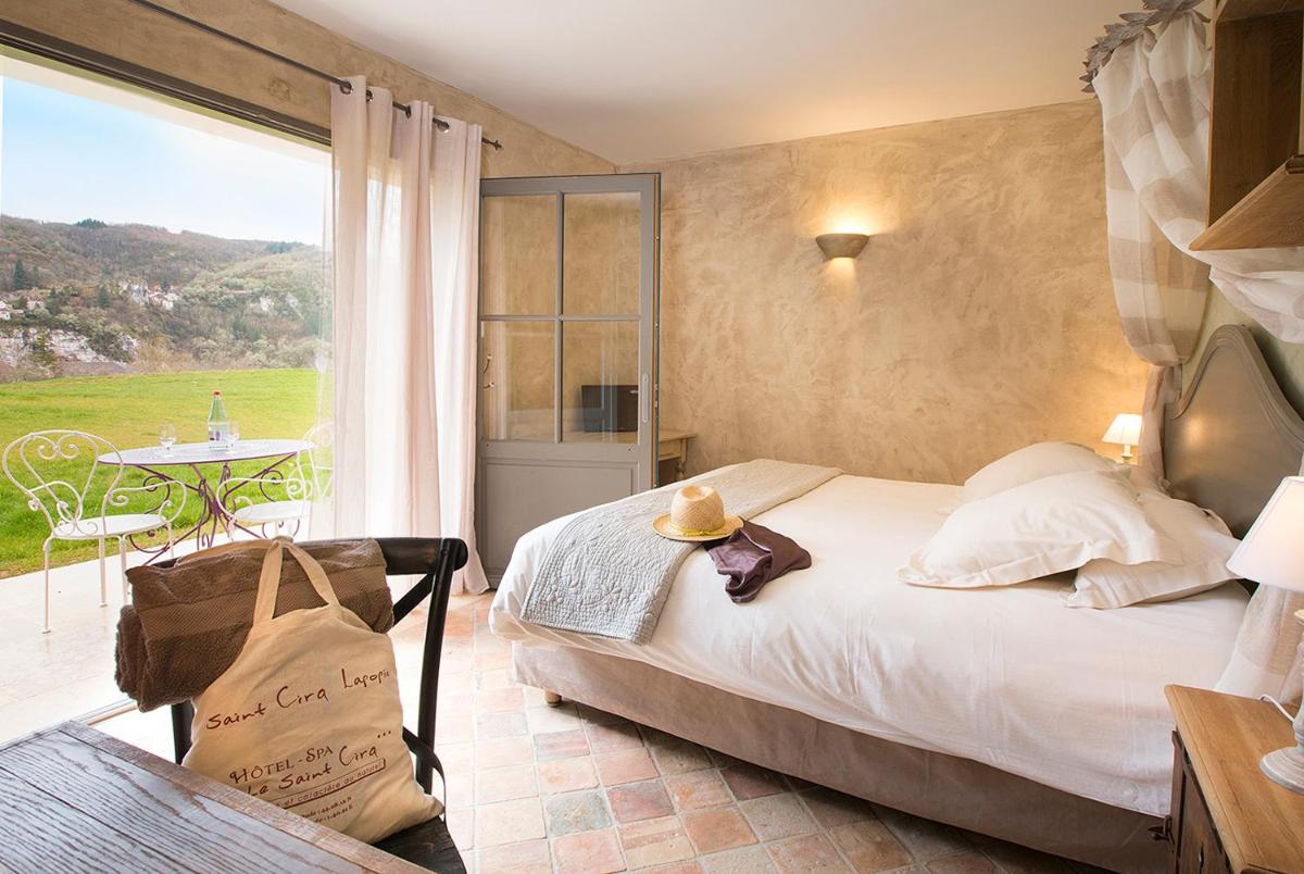 une chambre avec un lit et un balcon avec une table dans l'établissement Hôtel-Spa Le Saint Cirq, à Tour-de-Faure