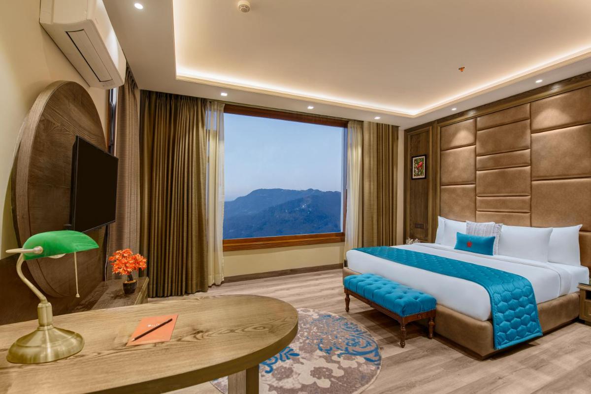 a hotel room with a bed and a large window at WelcomHeritage Elysium Resort & Spa in Shimla