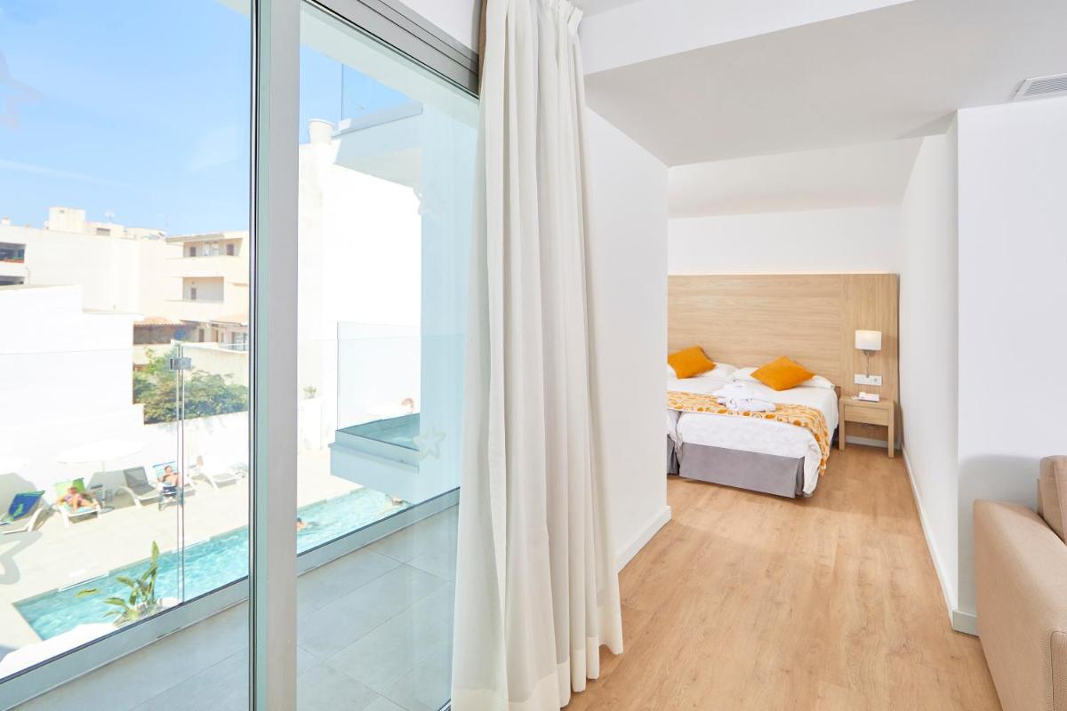 Un dormitorio con una cama y una ventana grande. en Hotel Ilusion Moreyo - Adults Only, en Cala Bona