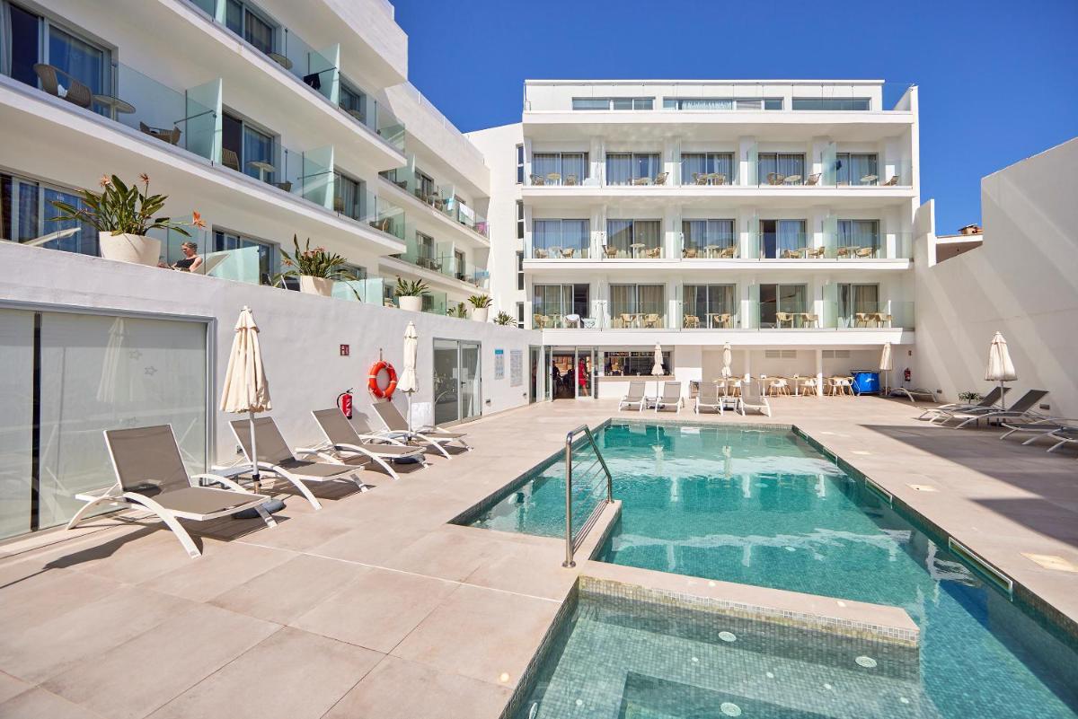 Una piscina con sillas y un edificio. en Hotel Ilusion Moreyo - Adults Only, en Cala Bona
