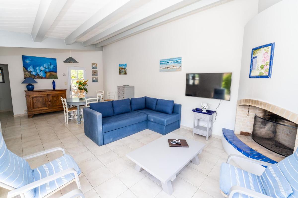 un salon avec un canapé bleu et une cheminée dans l'établissement Hôtel Restaurant & Spa Plaisir, au Bois-Plage-en-Ré