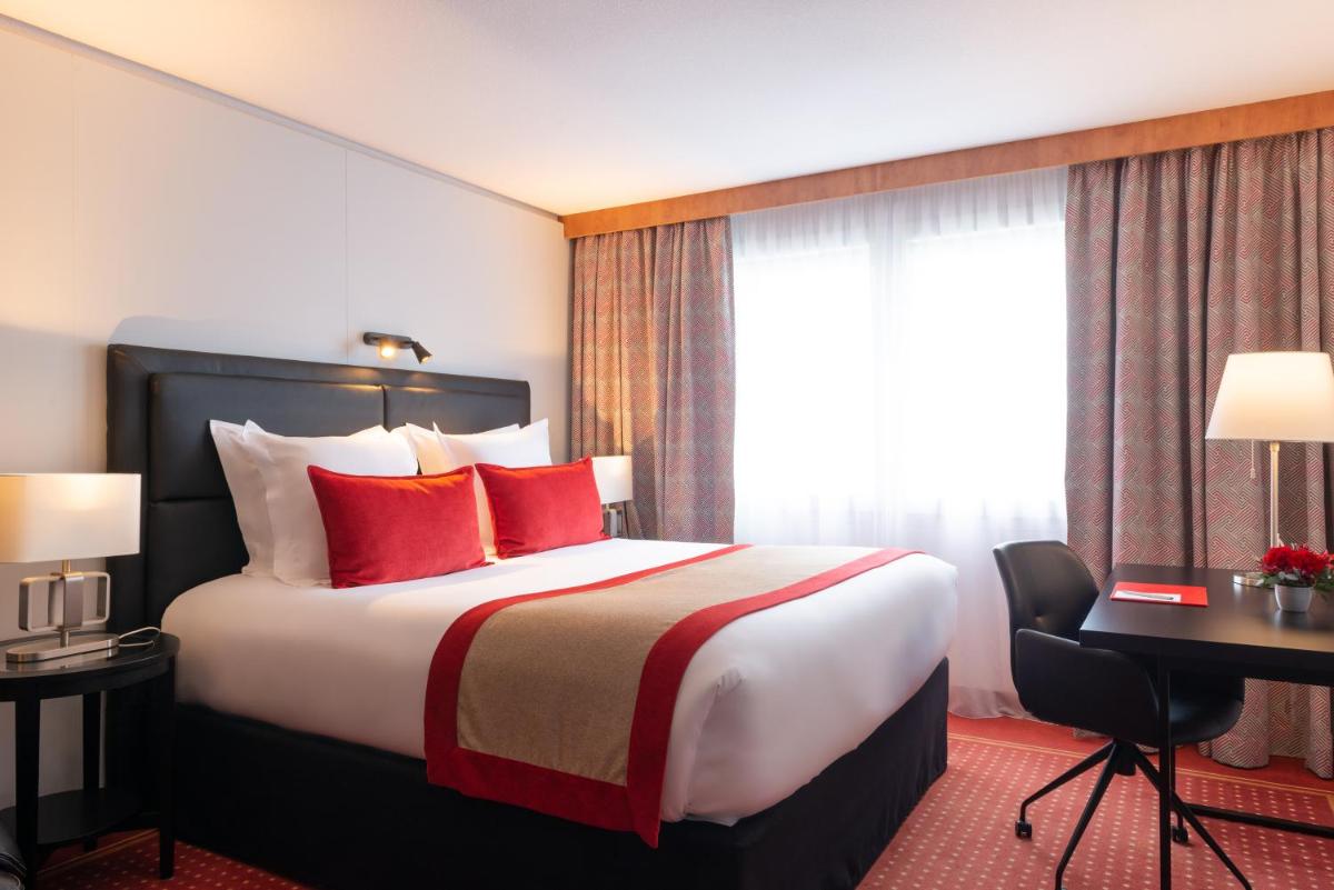 Cette chambre comprend un lit avec des oreillers rouges et une fenêtre. dans l'établissement Le M & Spa Bordeaux Aéroport by Hôtels & Préférence, à Mérignac