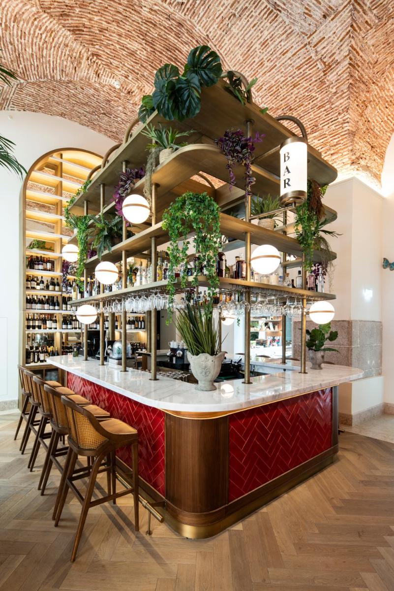 um restaurante com um bar com cadeiras e plantas em Palácio Ludovice Wine Experience Hotel em Lisboa