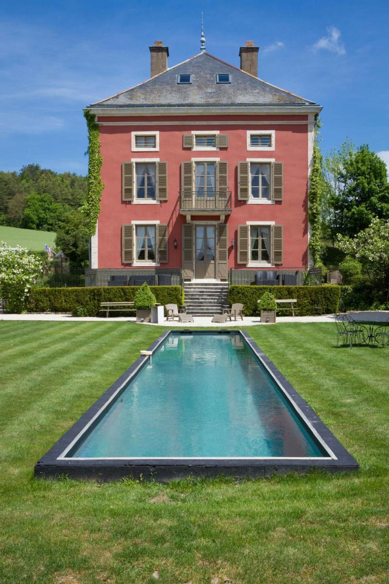 une grande maison avec une piscine devant dans l'établissement Château de Courban and Spa Nuxe, à Courban