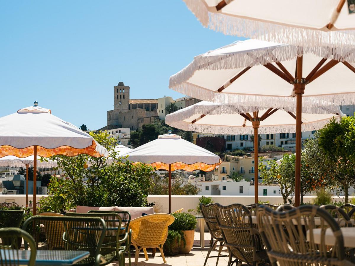 Un patio con mesas, sillas y sombrillas. en The Standard, Ibiza, en Ibiza