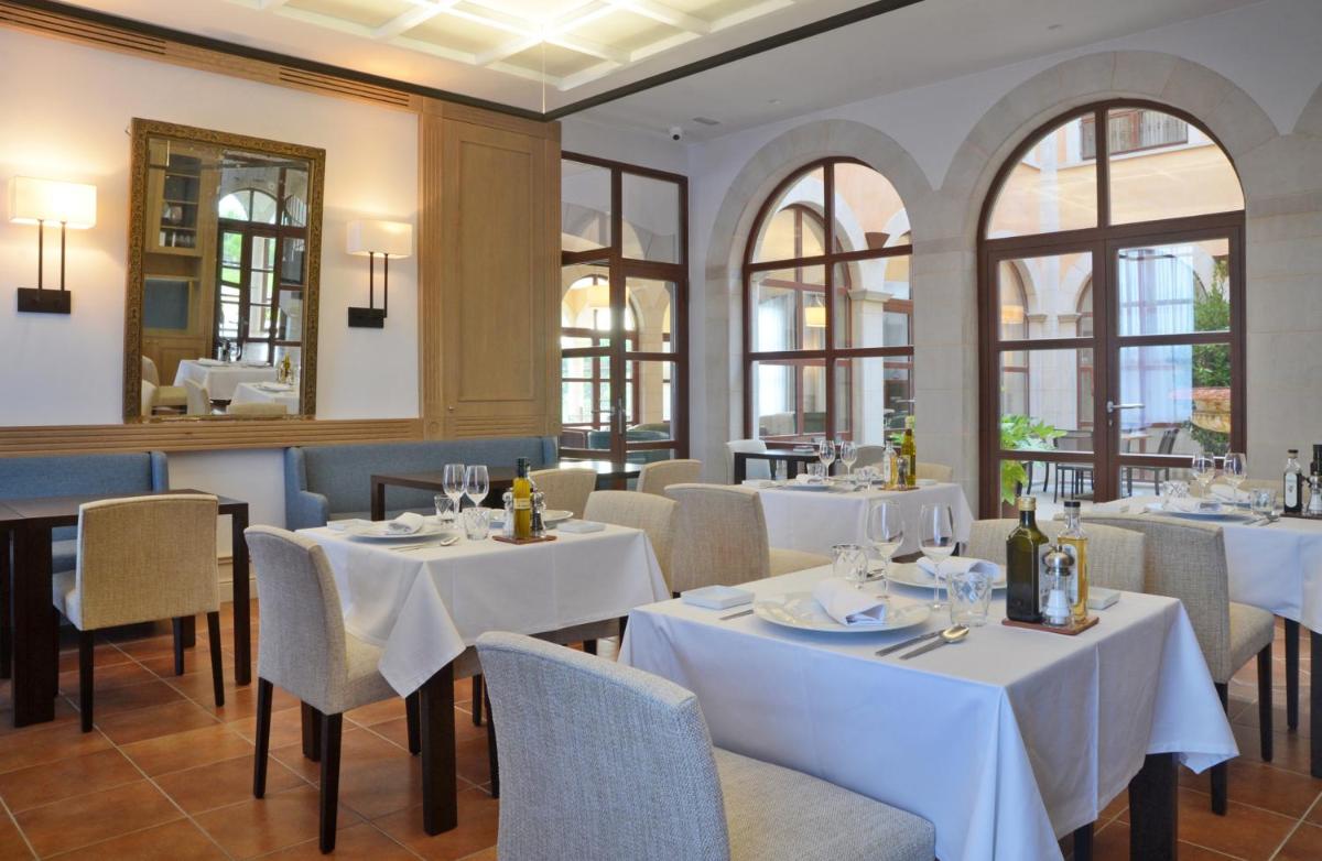 un restaurante con mesas y sillas blancas y un espejo en Casa Anamaria Hotel, en Ollers