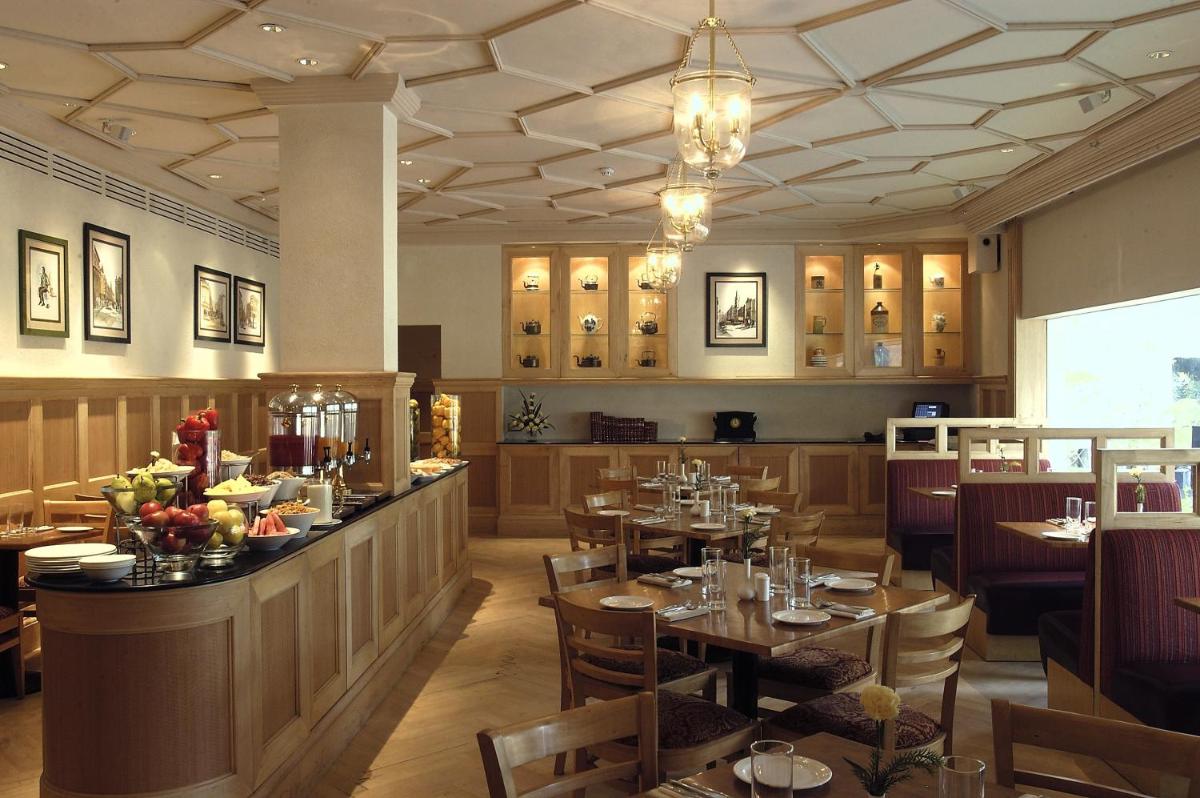 a restaurant with tables and chairs and a bar at The Claridges New Delhi in New Delhi a restaurant with tables and chairs and a bar at The Claridges New Delhi in New Delhi