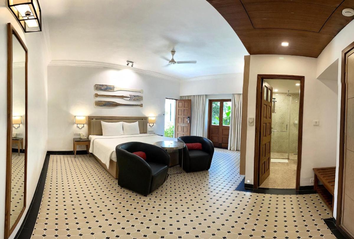 a hotel room with a bed and two chairs at Radisson Goa Candolim in Candolim