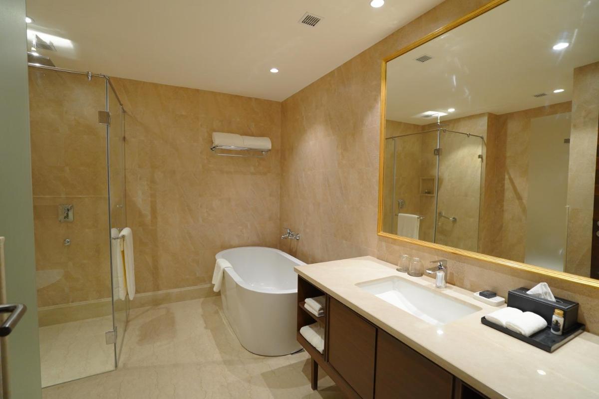 a bathroom with a tub and a sink and a mirror at Taj Tirupati in Tirupati