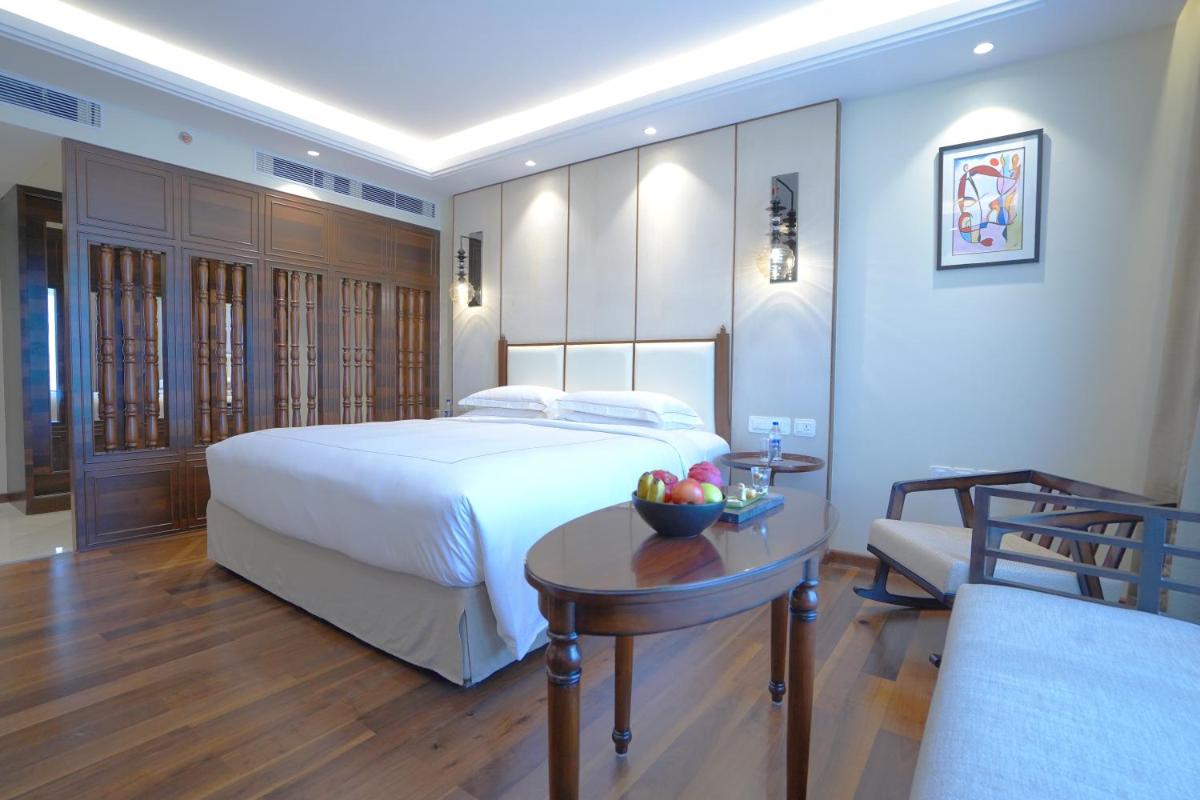 a bedroom with a bed and a table with a bowl of fruit at Taj Tirupati in Tirupati