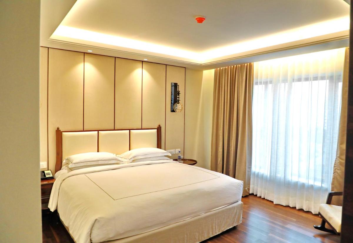 a bedroom with a large white bed and a window at Taj Tirupati in Tirupati