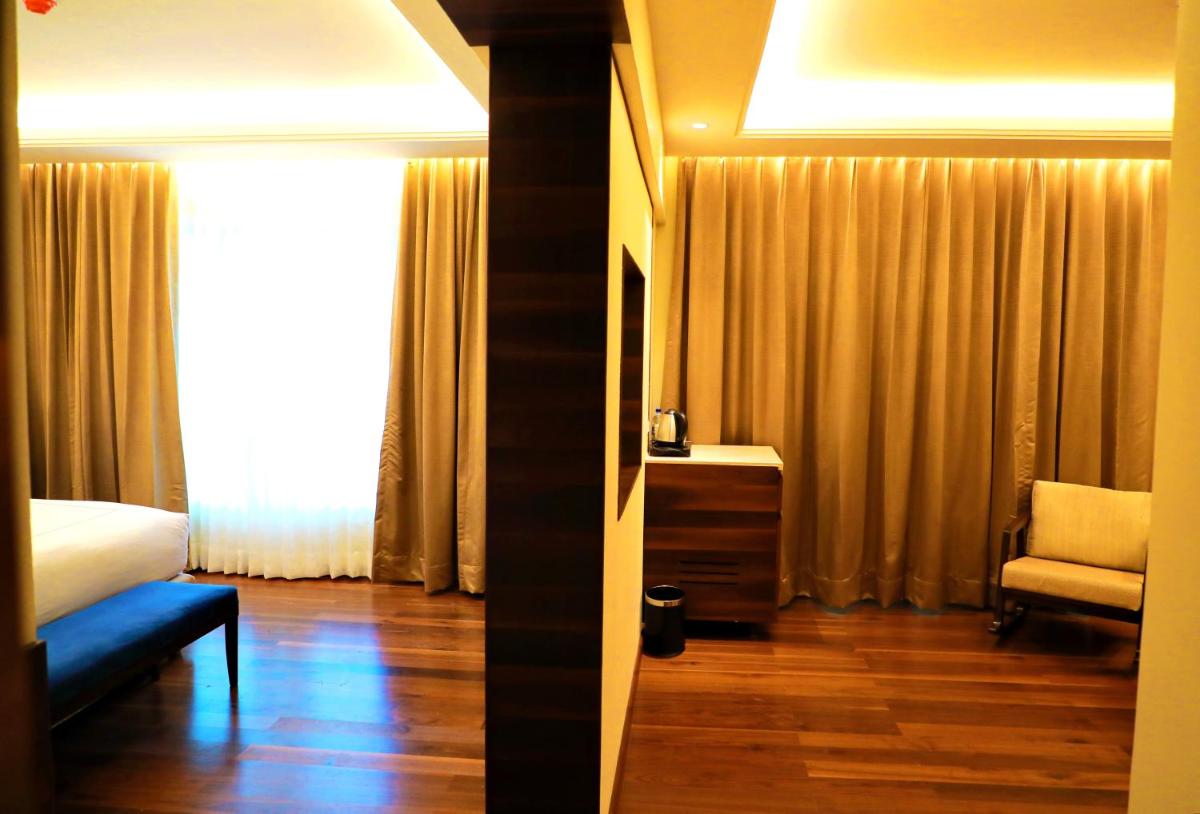 a bedroom with a bed and a chair and a window at Taj Tirupati in Tirupati