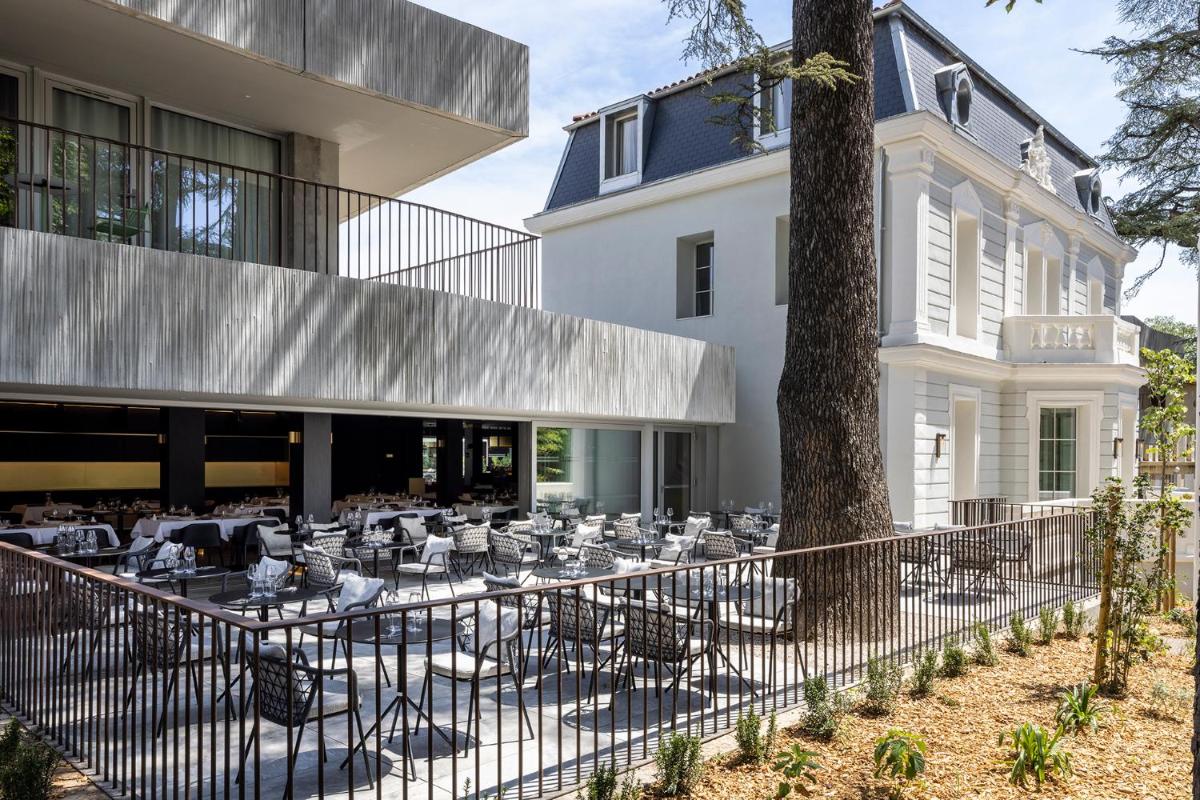 une terrasse extérieure avec des tables et des chaises devant un bâtiment dans l'établissement Hôtel Spa Restaurant Villa Castellane, à Gréoux-les-Bains