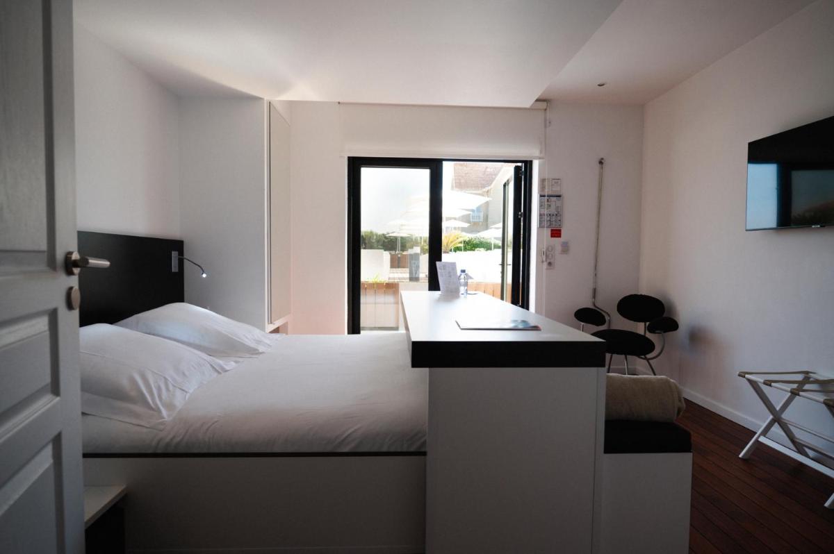 une chambre d'hôtel avec un lit, un bureau et une fenêtre dans l'établissement Le Grand Hotel de la Plage, à Biscarrosse-Plage