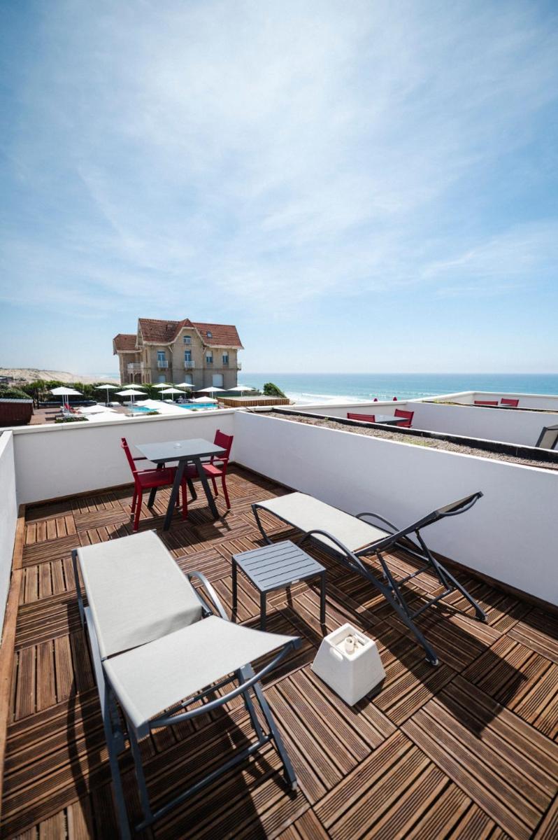 un balcon avec une table et des chaises et l'océan dans l'établissement Le Grand Hotel de la Plage, à Biscarrosse-Plage