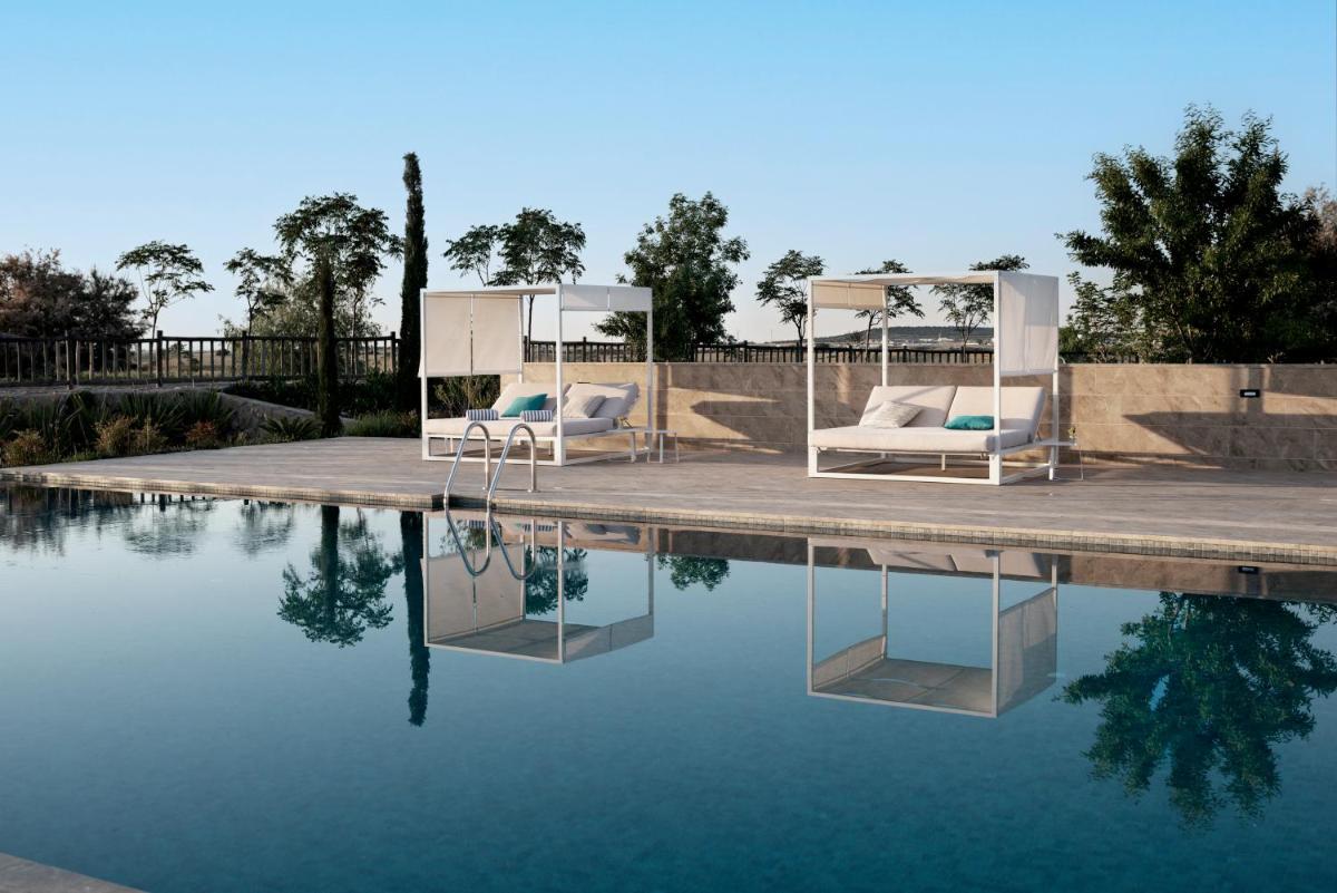 una piscina con 2 tumbonas junto al agua en Hospes Palacio de Arenales & Spa, en Cáceres