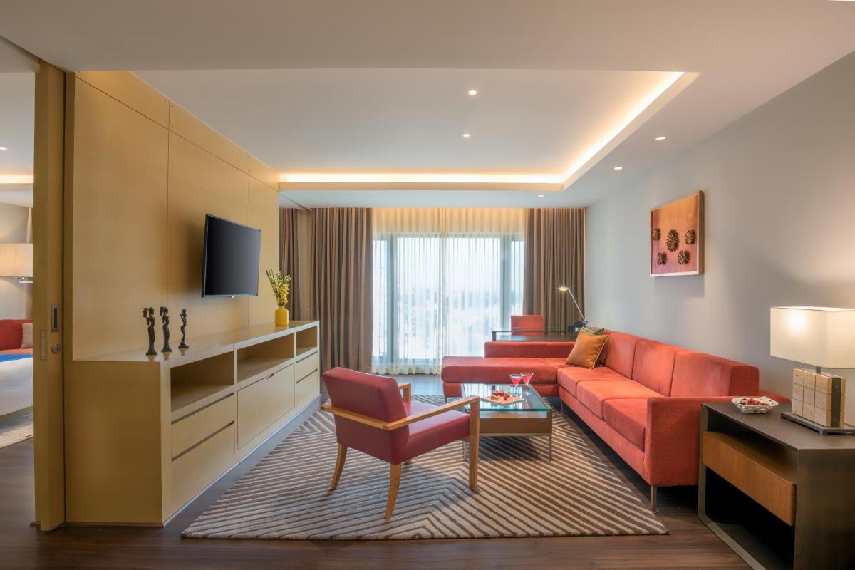 a living room with a red couch and a table at Feathers- A Radha Hotel, Chennai in Chennai